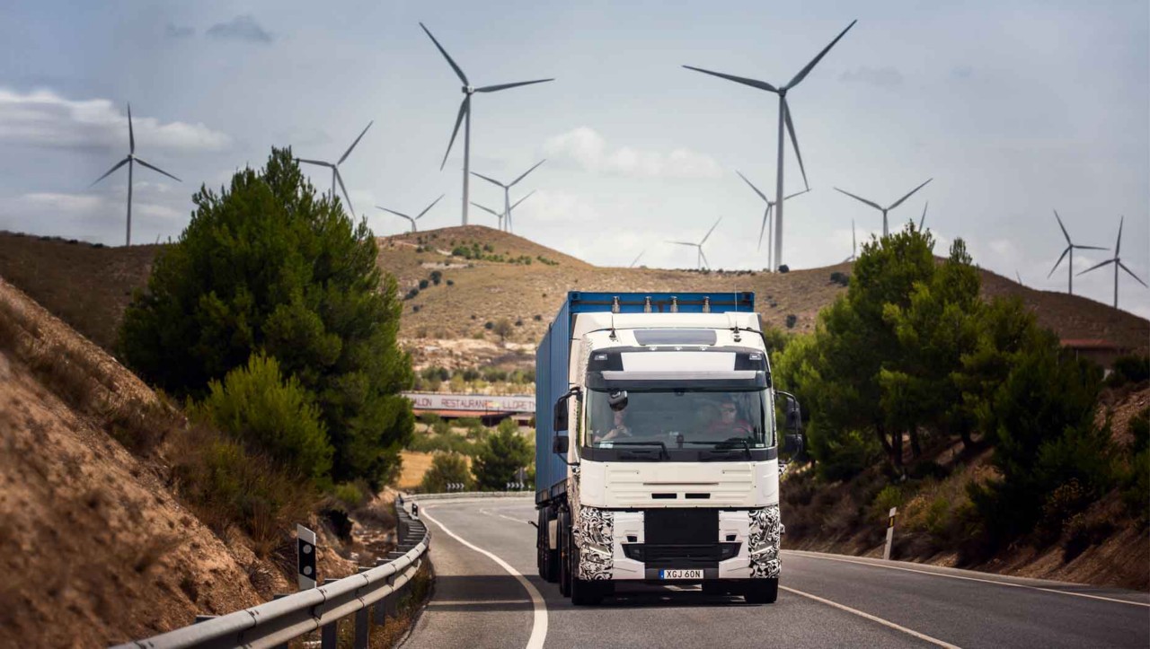 Un camion en phase de test sur une route d'Espagne avec des éoliennes en arrière-plan